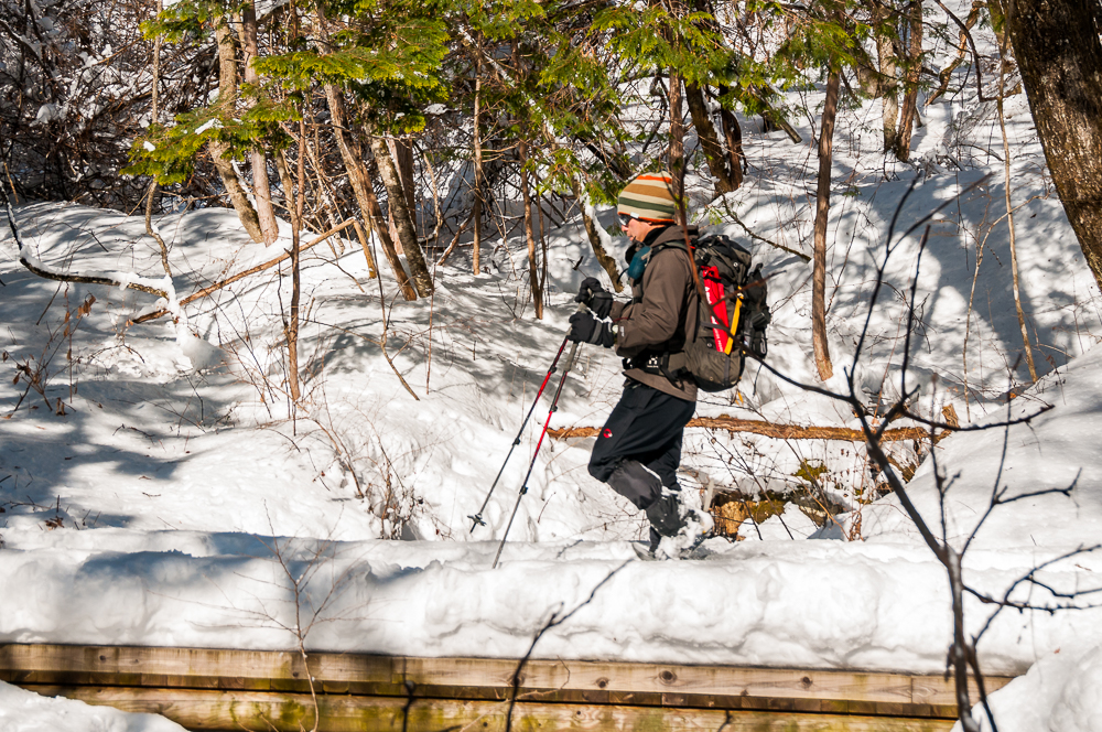 Man walking with snow shoes in the Jizo Pass along the old Hida Highway above Kiso-Fukishima, Nagano Prefecture, Japan.